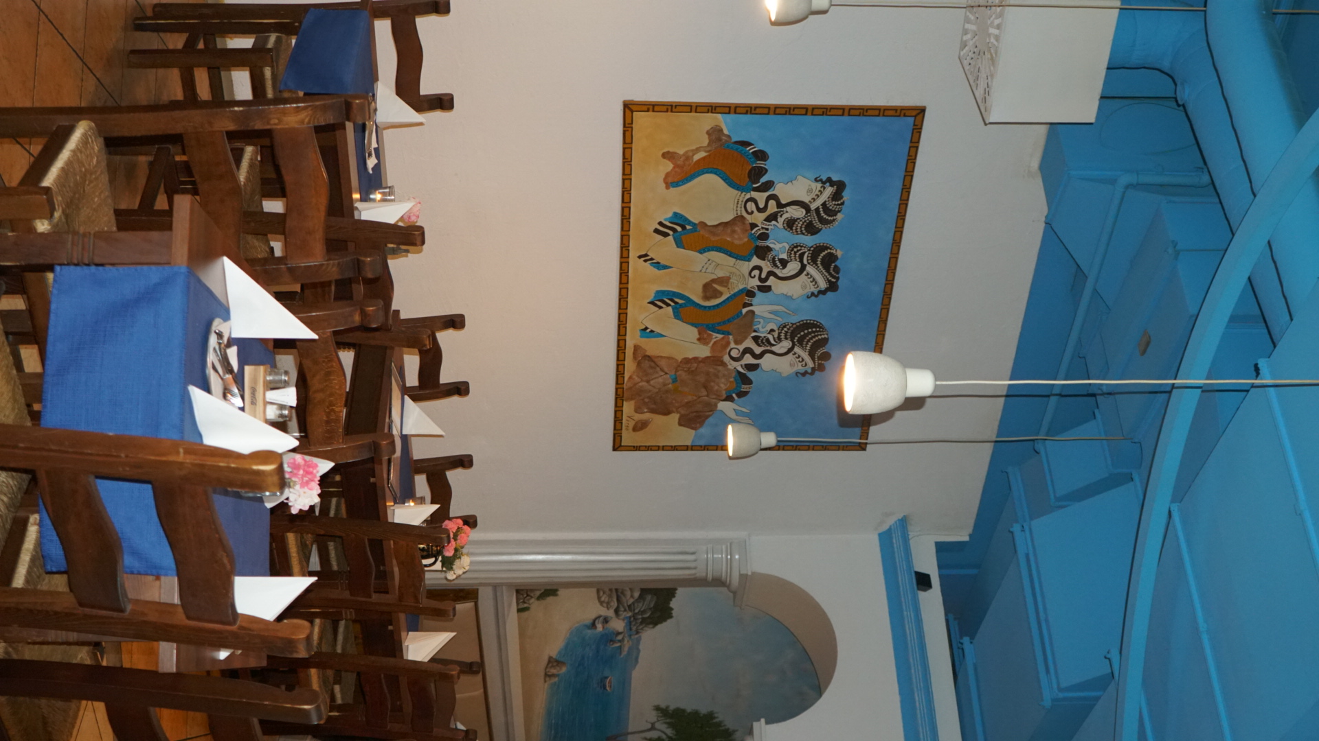 Heller Gastraum im El Greco mit minoischem Wandbild und blauen Tischläufern